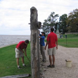 Three staff members removing pieces of a wooden palisade wall