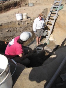 Two archaeologists talk while standing in an excavation unit
