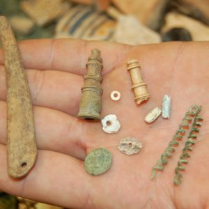Hand holding an assortment of small artifacts