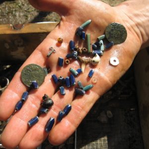 Hand holding an assortment of beads and coins