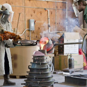 Workers pour molten copper alloy into mold