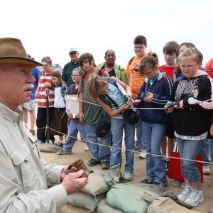 Archaeologist shows artifact to group of children