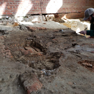 Archaeologist excavates brick and dirt church floor