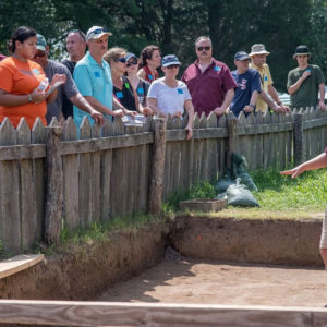 Archaeologist speaks to visitors behind a fence