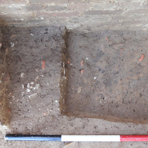 excavated trench beside a brick tower
