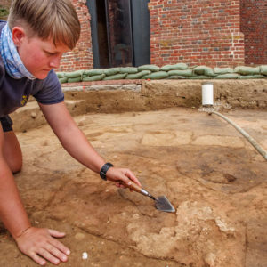 Archaeologist Caitlin Delmas excavates plaster at the west Church Tower excavation site.