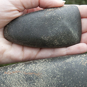 Hand holding rounded stone celt