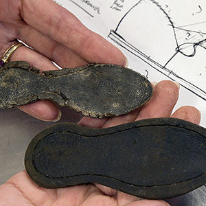 hands holding leather two soles of child's shoe