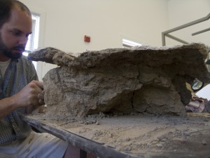 Conservator seated next to a large corroded armor piece
