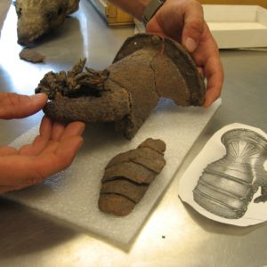 Conservator holding gauntlet next to reproduction drawing