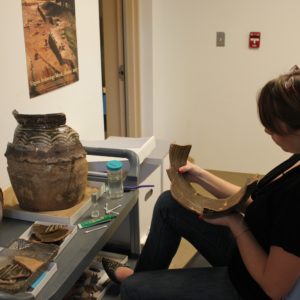 Curator mending an earthenware jar