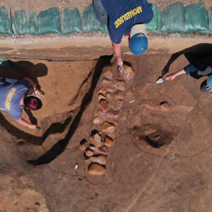 Staff Archaeologists Caitlin Delmas, Gabriel Brown, and Natalie Reid pose for a drone shot at the 1607 Burial Ground
