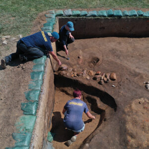 Staff Archaeologists Gabriel Brown, Natalie Reid, and Caitlin Delmas at work in the 1607 Burial Ground. The row of cobblestones is a foundation for a row house likely built in 1611. The modern recreation marking the foundation can be seen to the left of Gabriel.