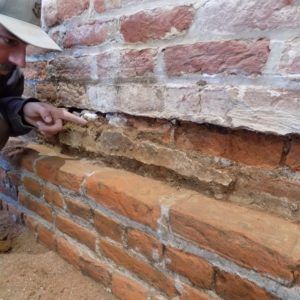 Archaeologist points to plaster adhered to a brick wall