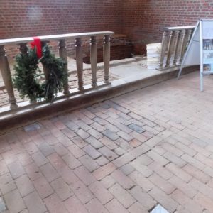 Excavation unit in brick church chancel behind railings with wreath