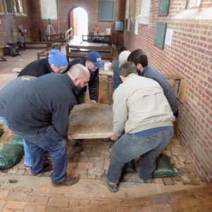 Group lifting tombstone in brick church