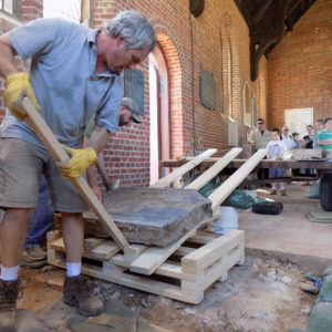 Conservators moving tombstone using inclined plane