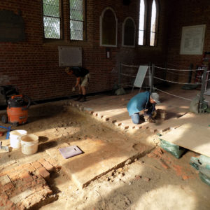 Archaeologists removing floor bricks inside church