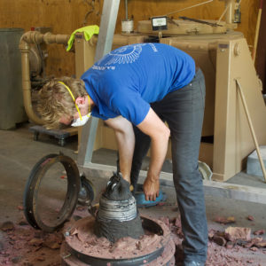 Worker removes cast bell from mold