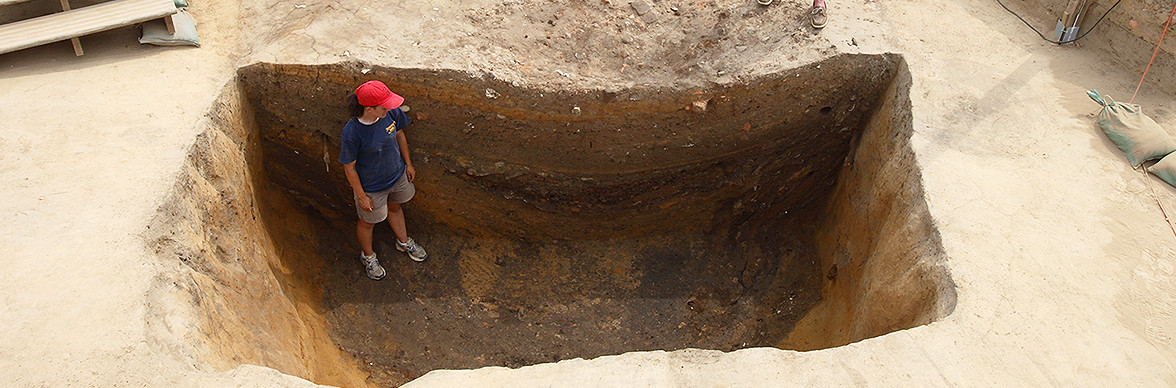 Archaeologist standing in deep excavation unit