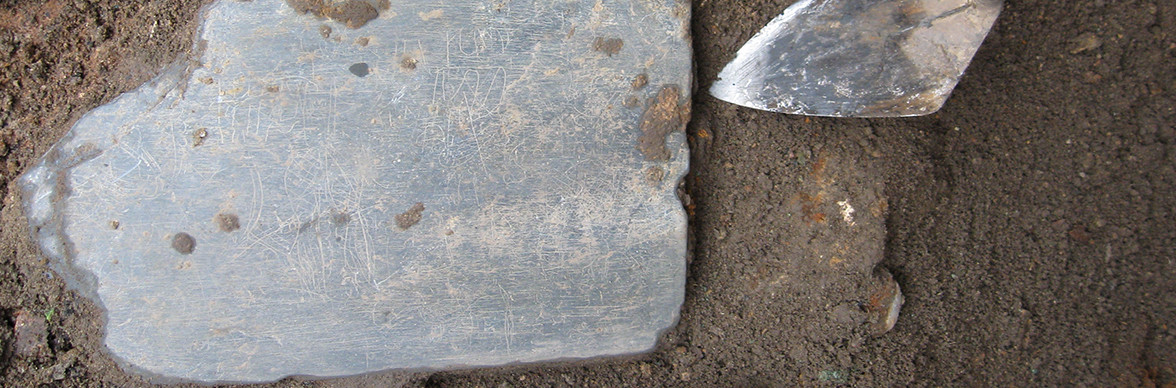 Slate tablet lying in situ next to trowel