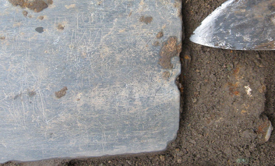 Slate tablet lying in situ next to trowel