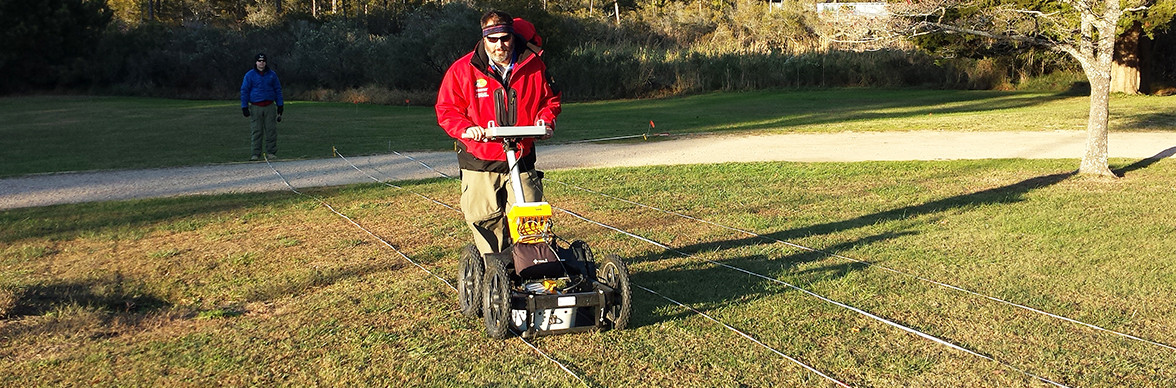 man pushes a ground penetrating radar unit along a transect line