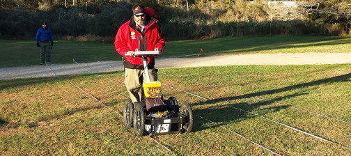 man pushes a ground penetrating radar unit along a transect line