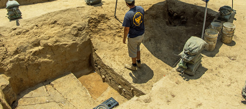 Archaeologist standing on a balk between two excavation units