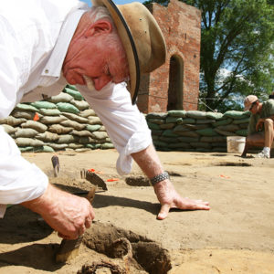 archaeologist brushing off a buried rapier hilt
