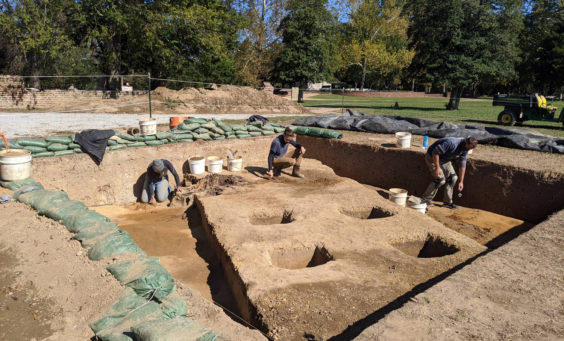 three archaeologists excavating in a large unit