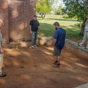 Four archaeologists stand in excavation unit