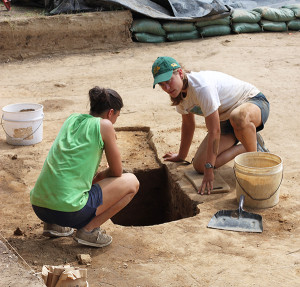 Two excavators kneeling beside an excavated feature