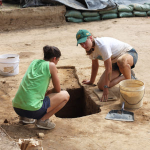 Two excavators kneeling beside an excavated feature