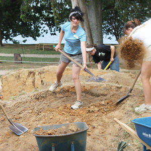 students shoveling dirt into wheelbarrows