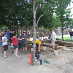Students and archaeologists talk to visitors while others excavate