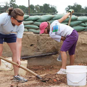students shoveling in an excavation unit lined with sandbags