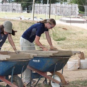 two students screening artifacts over wheelbarrows