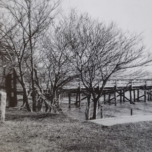 black and white photograph of a brick building and river dock