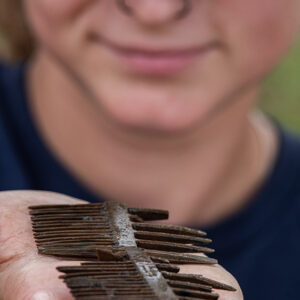 Archaeological Field Technician Ren Willis holds the wooden comb found in the Governor's Well.