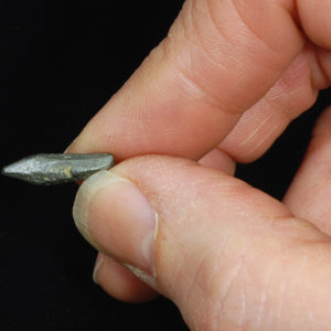 Researcher's hand holding small pointed piece of graphite