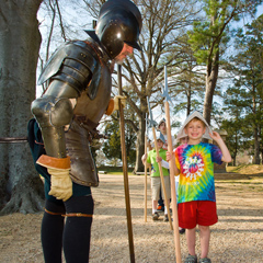 Man in historical armor watching children marching