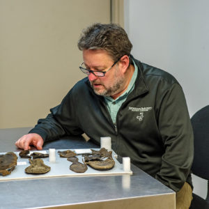 Archaeological Conservator Dr. Chris Wilkins examines some of the shoes found in the fort's second well.