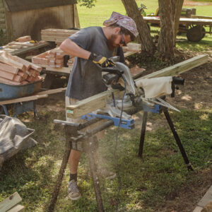 Archaeological Field Technician Josh Barber cuts posts for use in the burial structures.