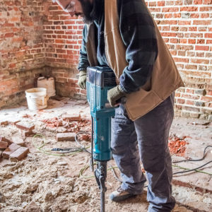 Archaeologist uses a jackhammer to excavate the floor of a brick church tower