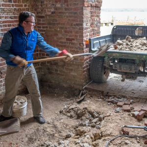 Archaeologist shovels concrete into truck bed