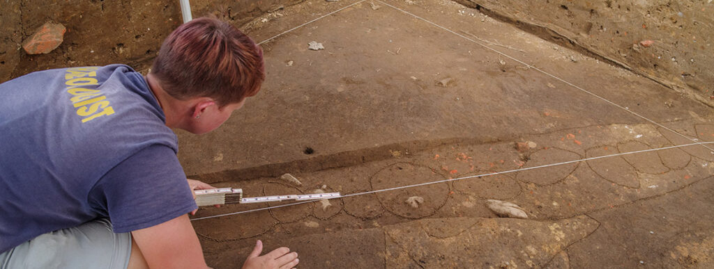 Staff Archaeologist Caitlin Delmas takes measurements of the postholes in a palisade running through the 1607 Burial Ground.
