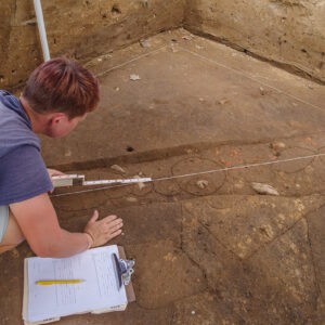 Staff Archaeologist Caitlin Delmas takes measurements of a palisade that cuts (and thus postdates) several features in the 1607 Burial Ground.