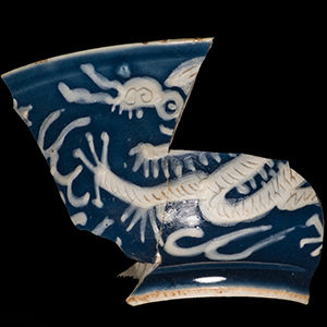 Photo of a blue Chinese porcelain bowl with white slip decoration depicting a dragon