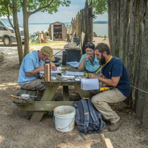 Archaeologists sitting at a bend completing paperwork
